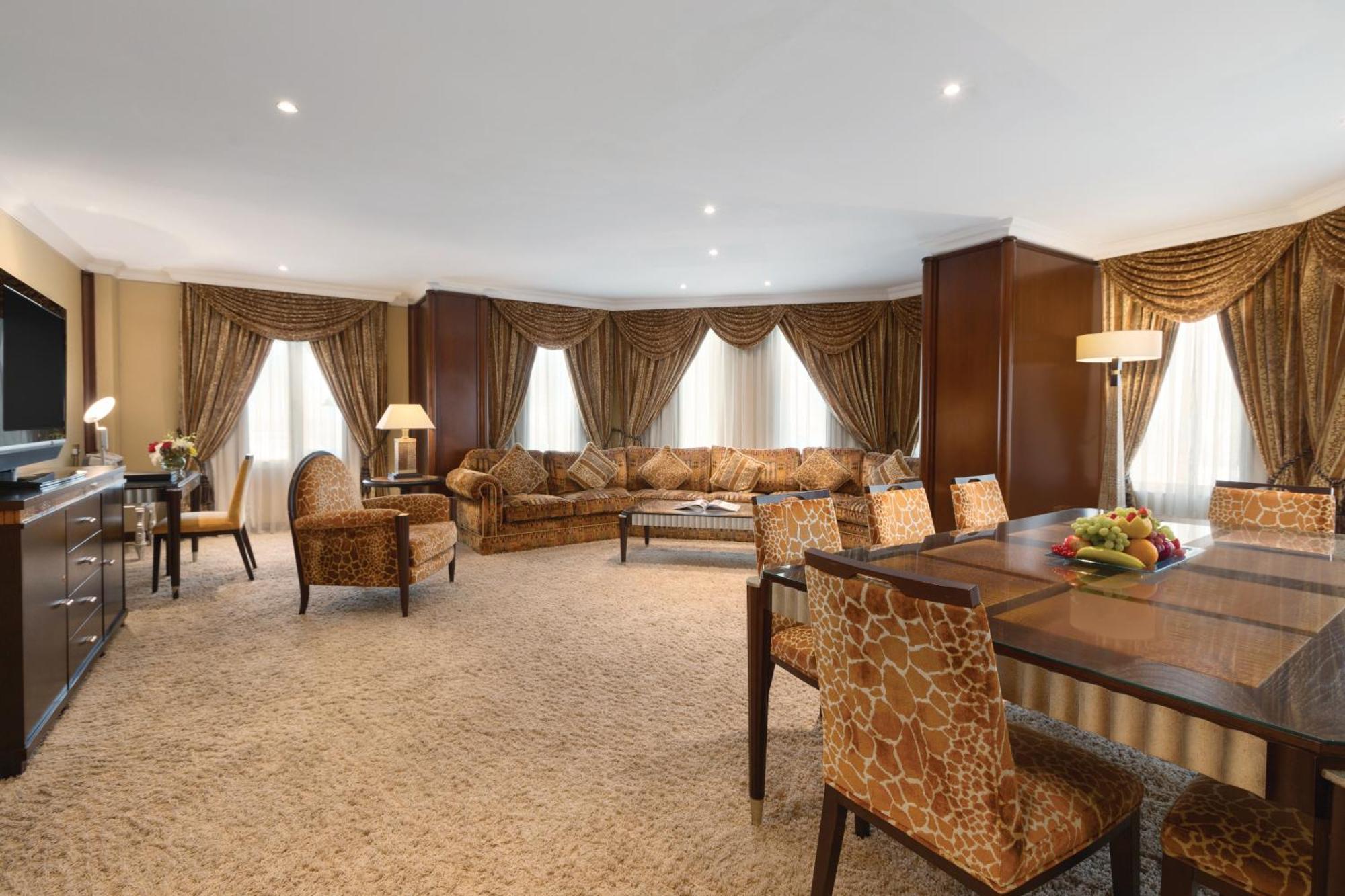 Grand Regency Doha, Trademark Collection By Wyndham מראה חיצוני תמונה The photo shows a spacious and elegantly designed living area. There are large windows dressed with luxurious curtains, allowing natural light to fill the room. The seating arrangement features a comfortable sofa with various cushions and several sty