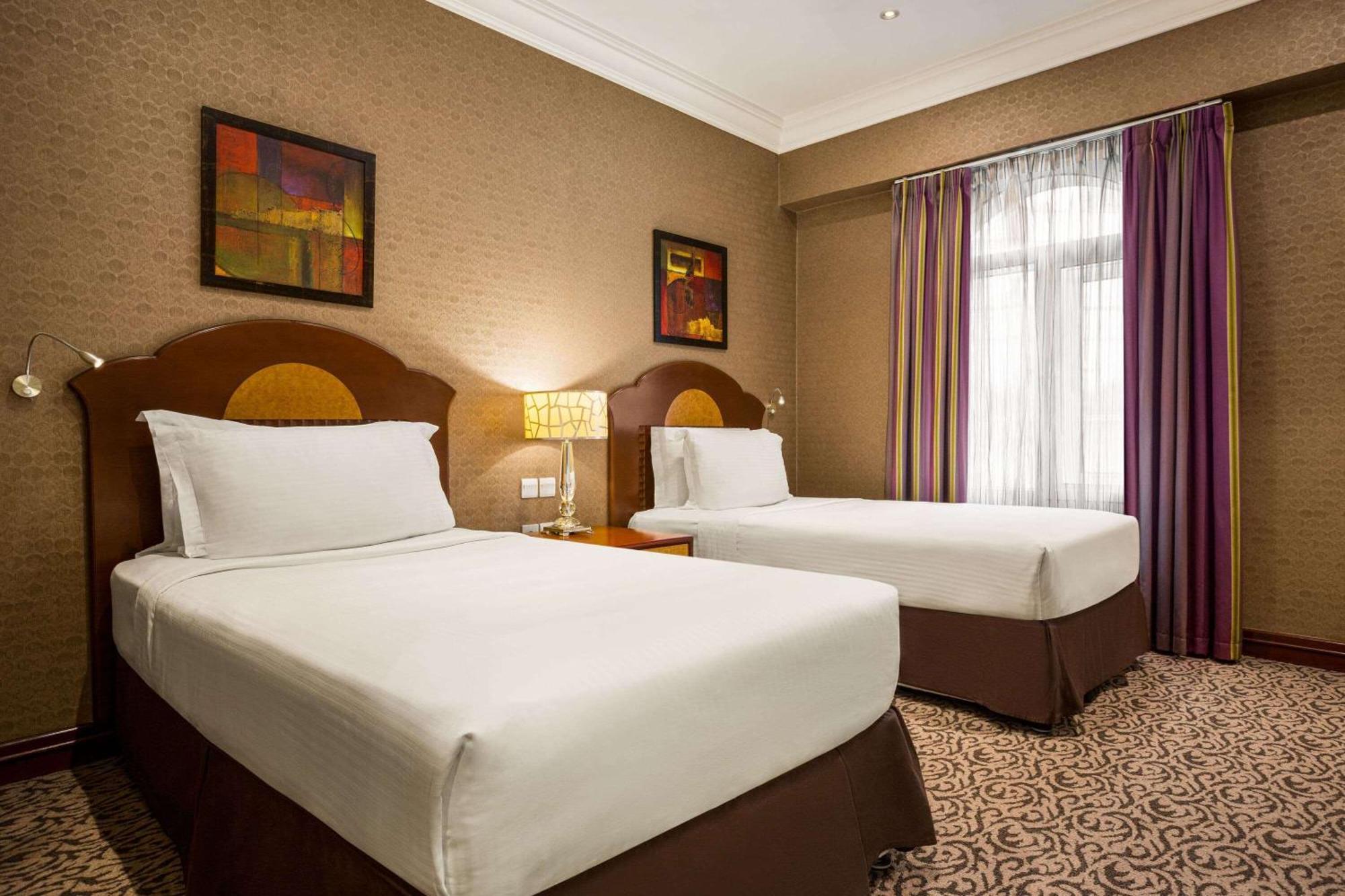 Grand Regency Doha, Trademark Collection By Wyndham מראה חיצוני תמונה The photo shows a hotel room featuring two single beds with white bedding and dark brown upholstered headboards. There is a bedside table with a lamp between the beds. On the walls are two abstract paintings, and large windows dressed with sheer curt